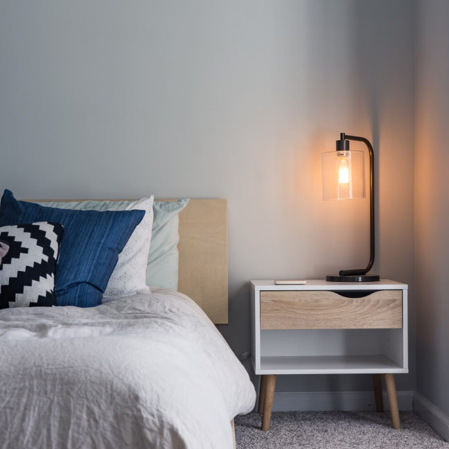 a bedroom with a bed, nightstand, and lamp